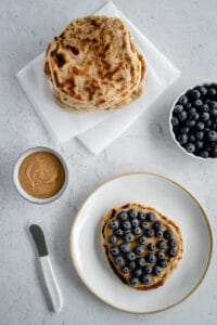 Top down view of naan bread with peanut butter and blueberries