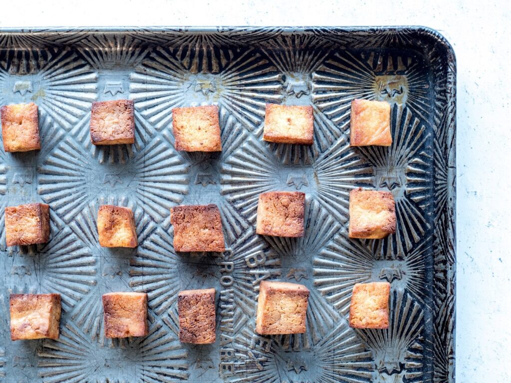 Top down view of a sheet pan covered with squares of baked tofu