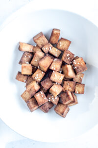 Close up view of a bowl filled with tofu and sesame seeds