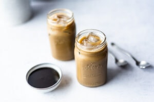 Two mason jars filled with molasses flavored milk next to a small bowl of molasses