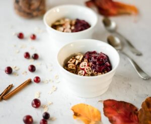 Two bowls of hot cereal surrounded by fall leaves and cinnamon sticks