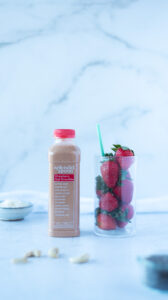 Bottle of smoothie next to glass of berries