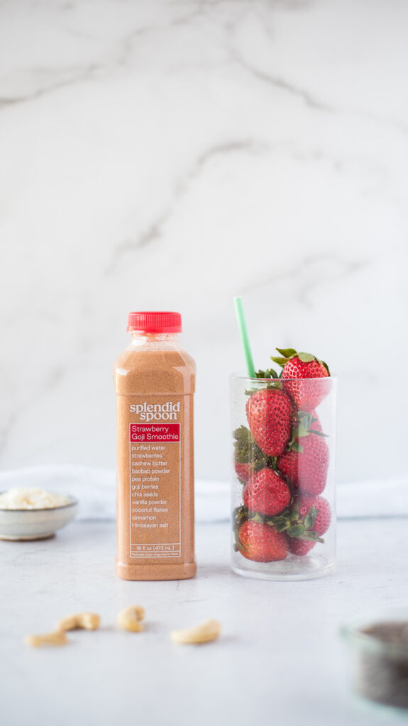Bottle of smoothie next to glass of strawberries