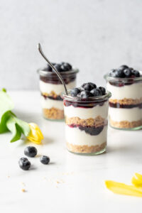 Three jars of blueberry cheesecake next to yellow tulips