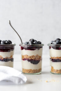 Three jars of blueberry cheesecake and one has a spoon in it