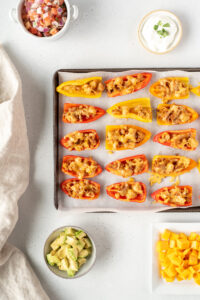 Pan of mini pepper nachos surrounded by condiments