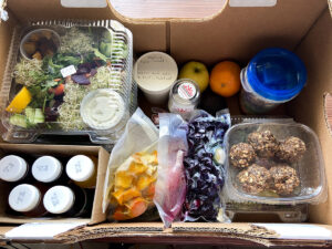 Box filled with juices, smoothie packs and salads