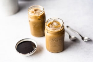 Two jars of molasses milk next to two spoons