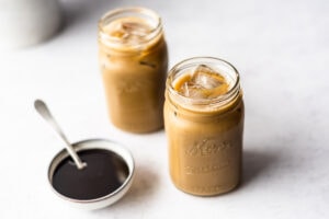 Two jars full of molasses milk next to a bowl of molasses