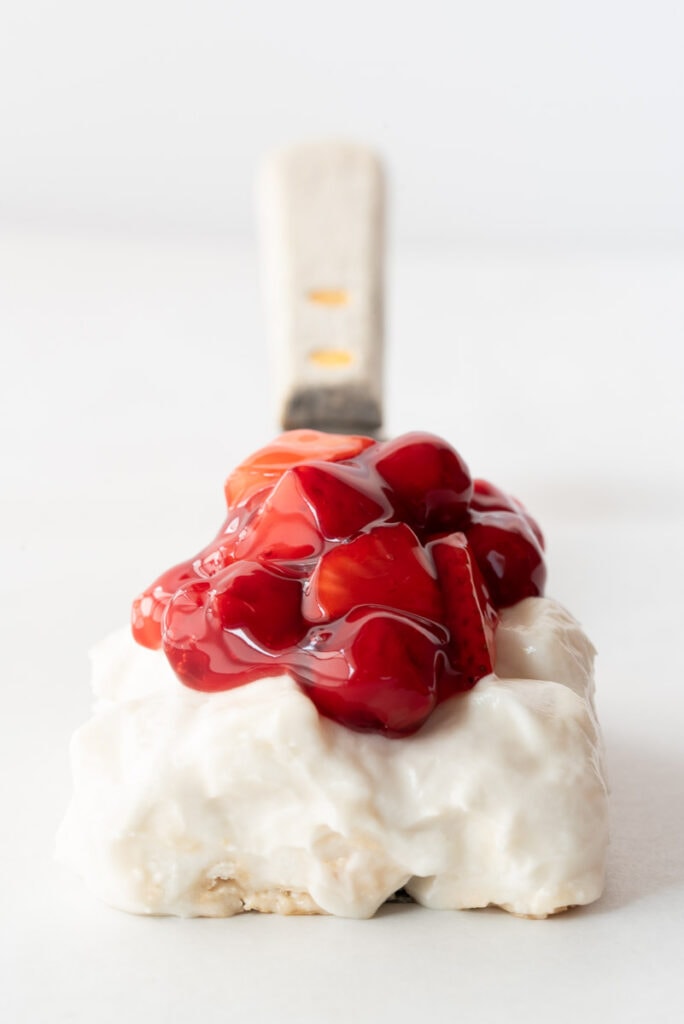 Spatula with one serving of meringue dessert and cherries on it