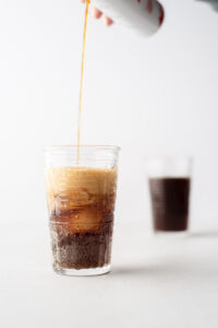 Two glasses of cacao fruit soda while one is being filled