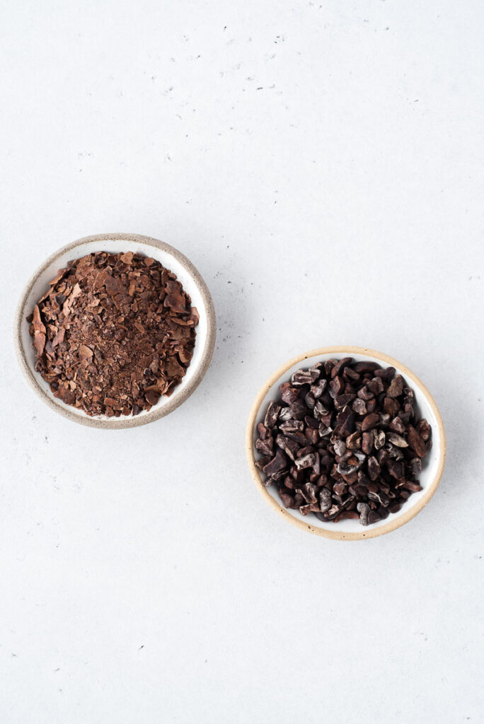 Top down view of small bowls of cacao husk and cacao nibs