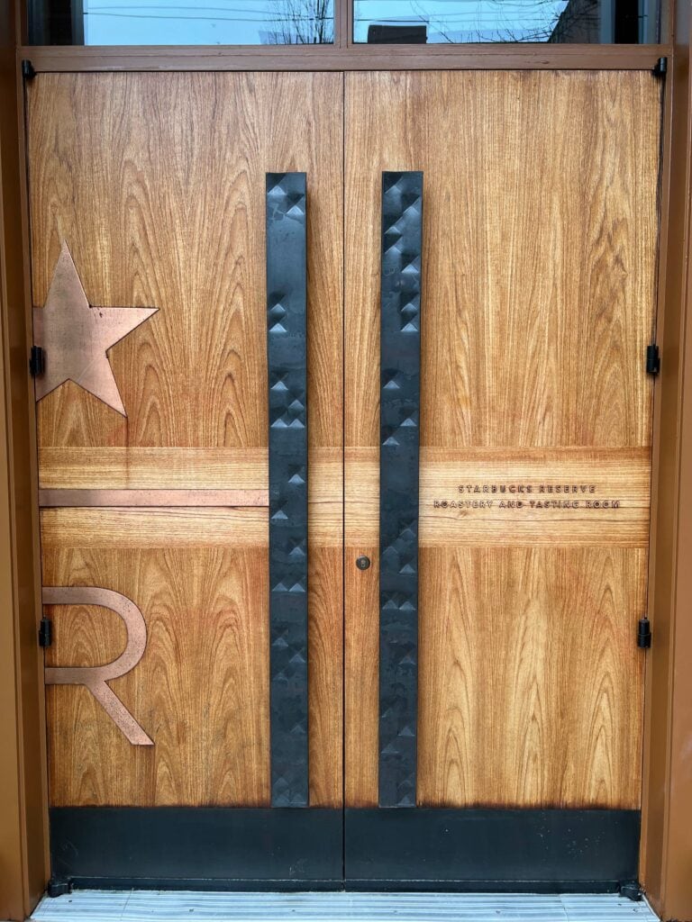 Large wooden front doors with black metal handles