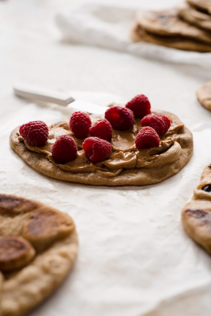 Naan bread topped with peanut butter and raspberries
