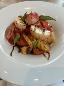 White bowl filled with tomatoes, nectarines and basil