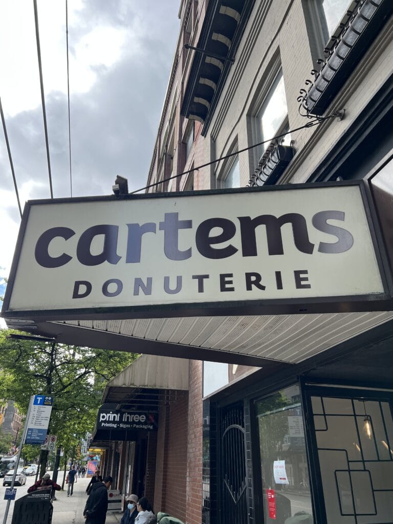 White sign with brown lettering that says Cartems donuterie