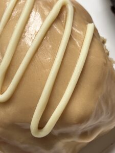 Close up of donut with light brown frosting and white stripes