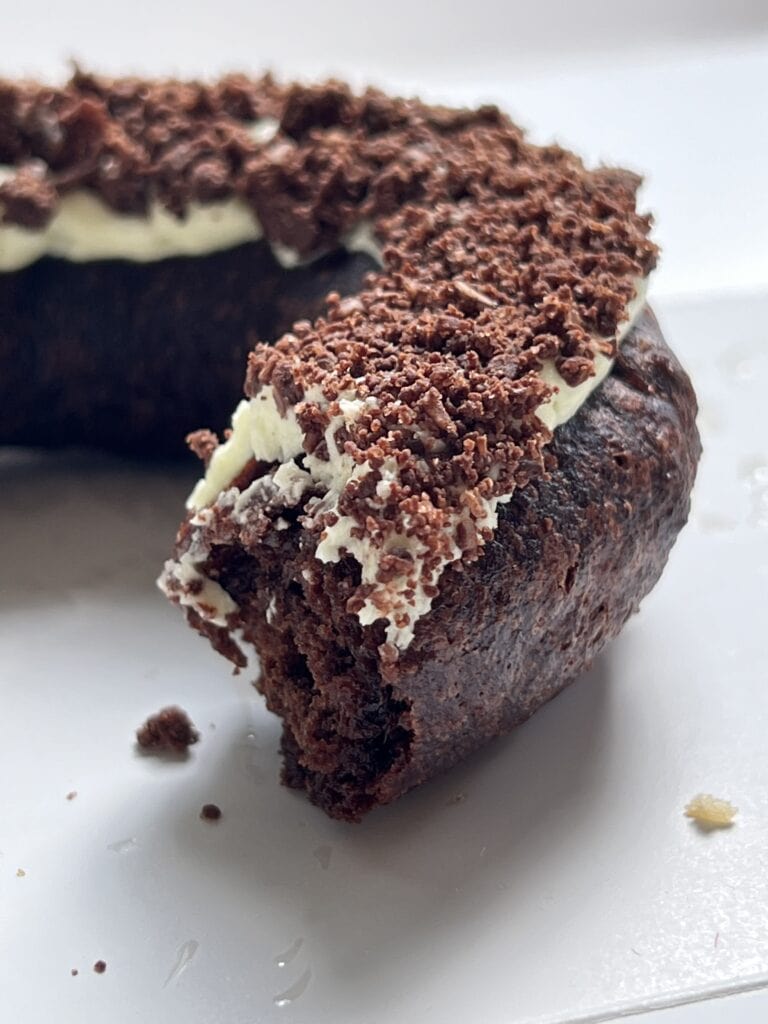 Close up of a chocolate donut with creamy frosting and chocolate crumbles
