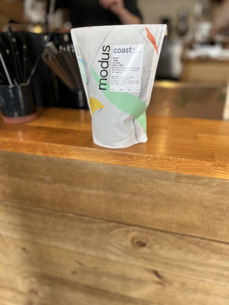 Wooden counter with a white bag on it full of coffee