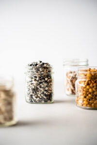 Four jars of colorful beans, in the center a small jar filled with black and white swirled beans