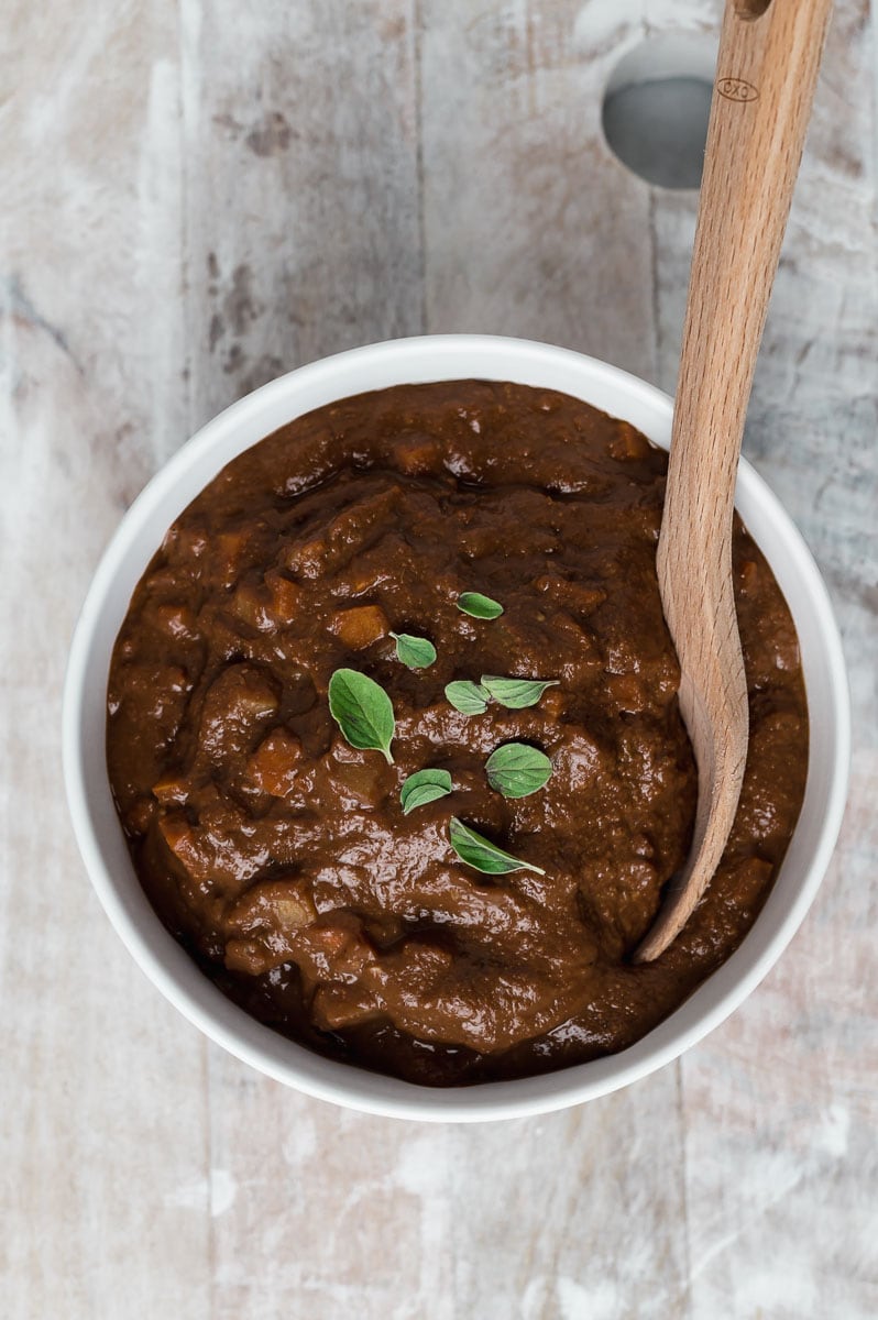 Top down view of a bowl of mole with a wooden spoon