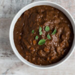 Top down view of a white bowl filled with brown mole sauce