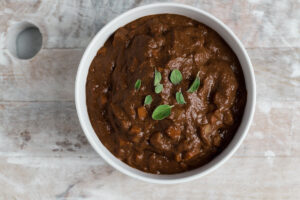 Top down view of a white bowl filled with brown mole sauce