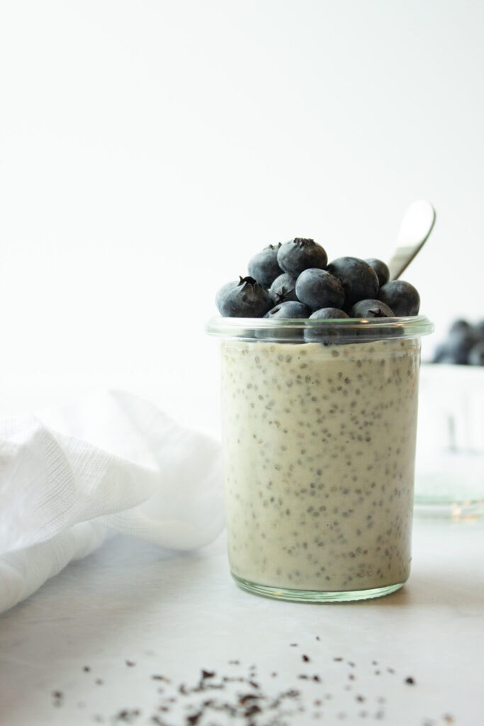 Single jar chia pudding topped with blueberries next to a napkin