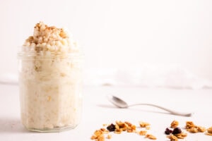 Jar of rice pudding next to granola and a spoon
