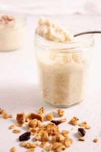 Jar of rice pudding with a spoonful balanced on top next to granola