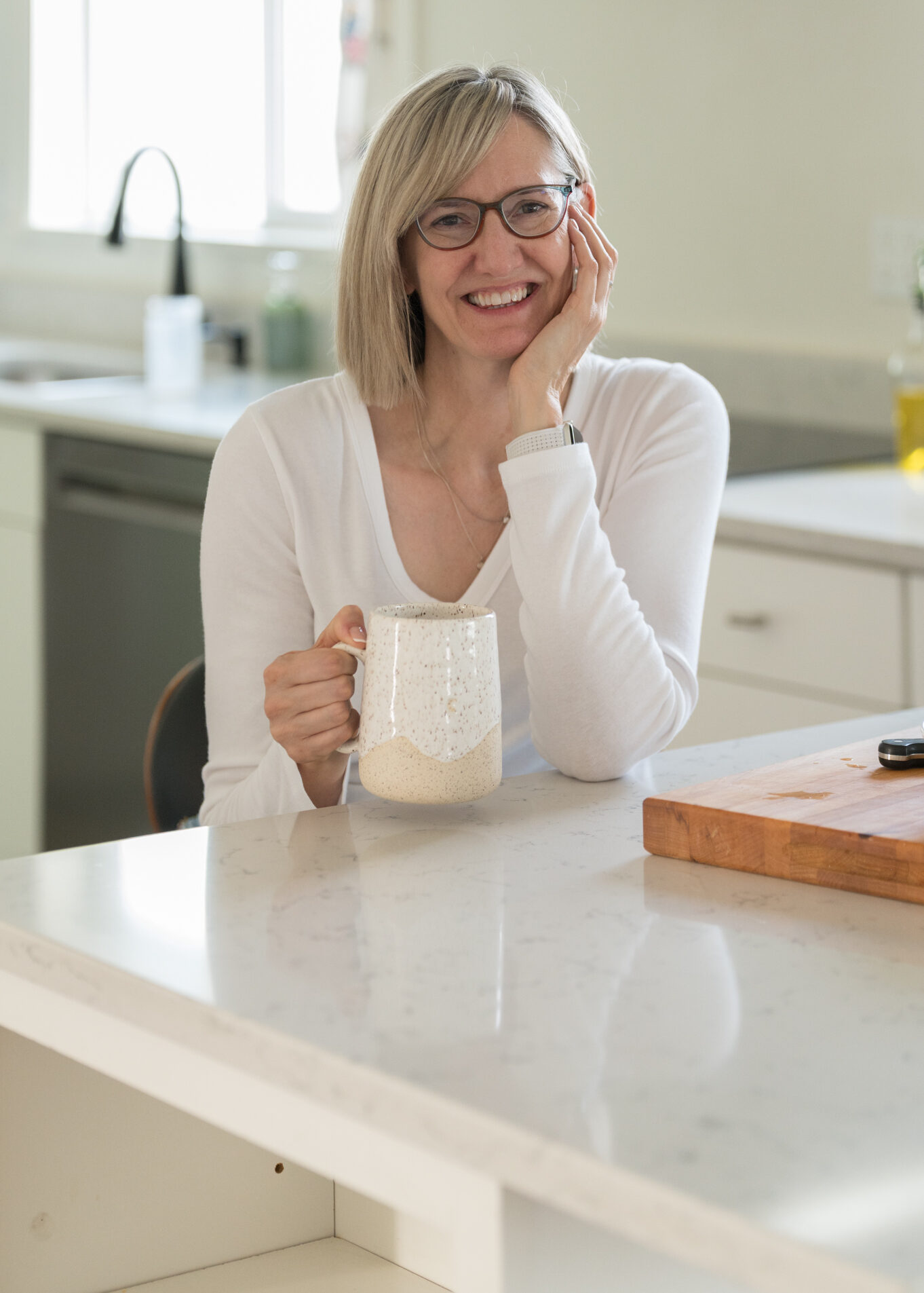 Woman seated in a kitchen holding a coffee cup