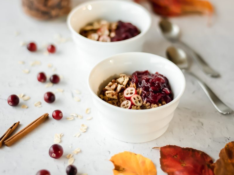 Two bowls of hot cereal surrounded by fall leaves and cinnamon sticks