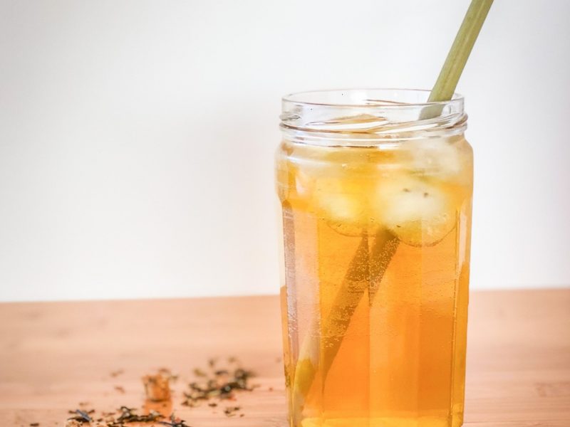 Loose tea on a table next to a glass of iced tea with a straw