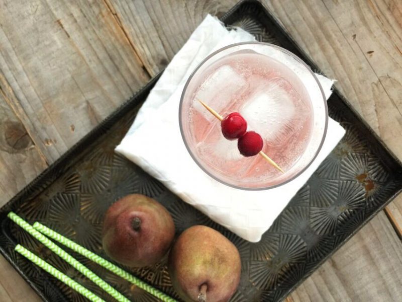 Top down view of an iced pink drink next to straws and pears