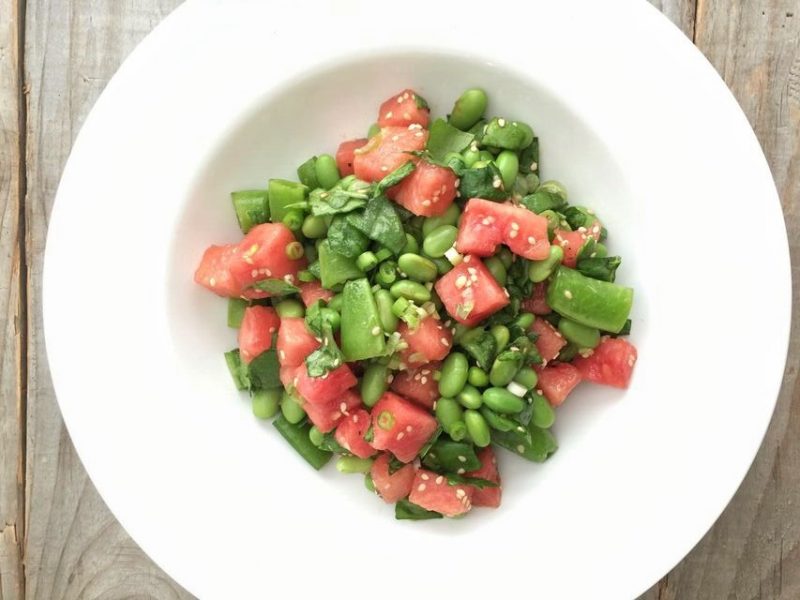 White bowl filled with watermelon, snap peas and edamame
