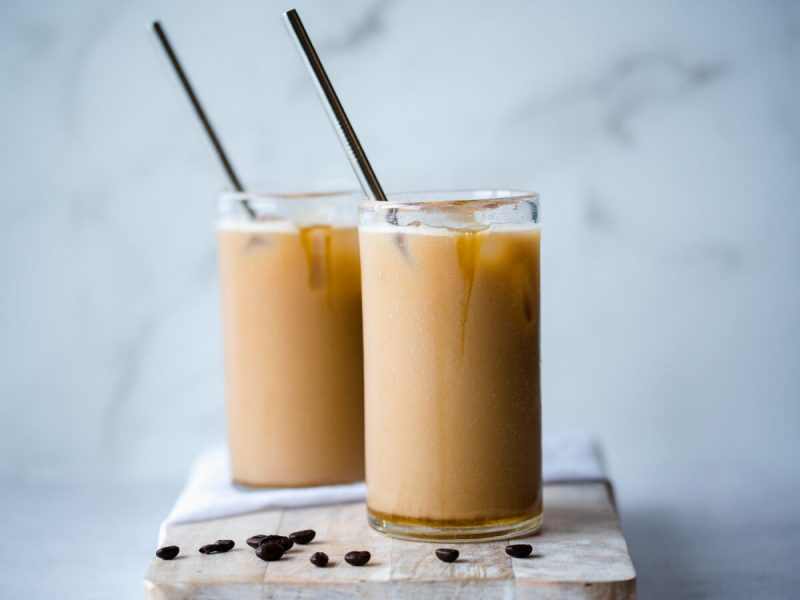 Two glasses full of iced coffee with straws