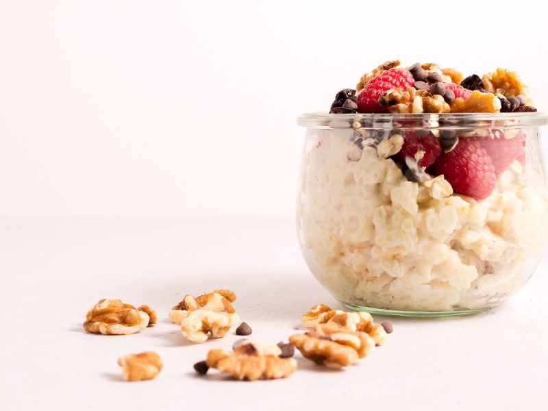 Glass bowl filled with rice pudding and fruit next to some walnuts