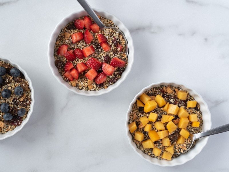 Top down view of 3 bowls of cereal with fruit