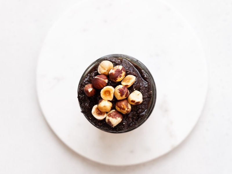 Top down view of jar of homemade nutella topped with hazelnuts