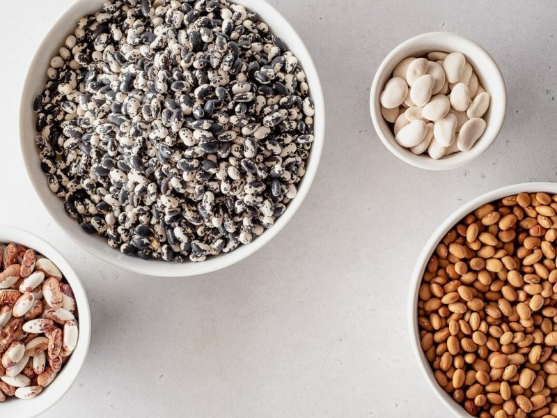 Four bowls of differing sizes viewed from the top, all filled with different colored dry beans