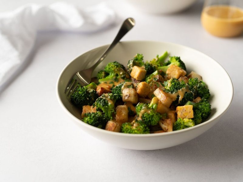 White bowl filled with broccoli, potatoes and tempeh