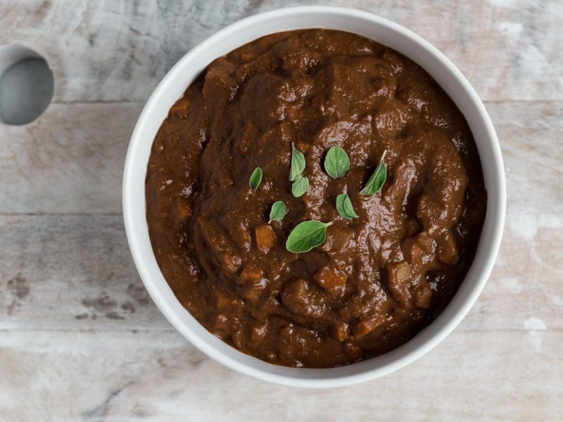 Top down view of a white bowl filled with brown mole sauce