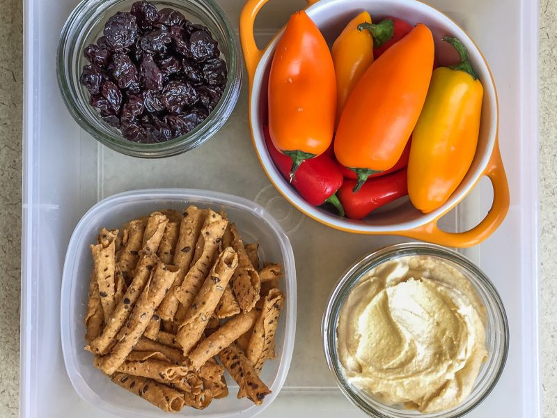 Healthy work snacks dried cherries, sweet peppers, hummus, tortilla chips